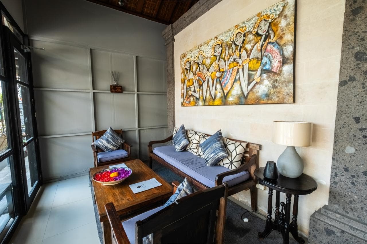 Cozy lounge seating area with sofa, armchairs and a framed Balinese dance artwork at T Glow Spa Ubud