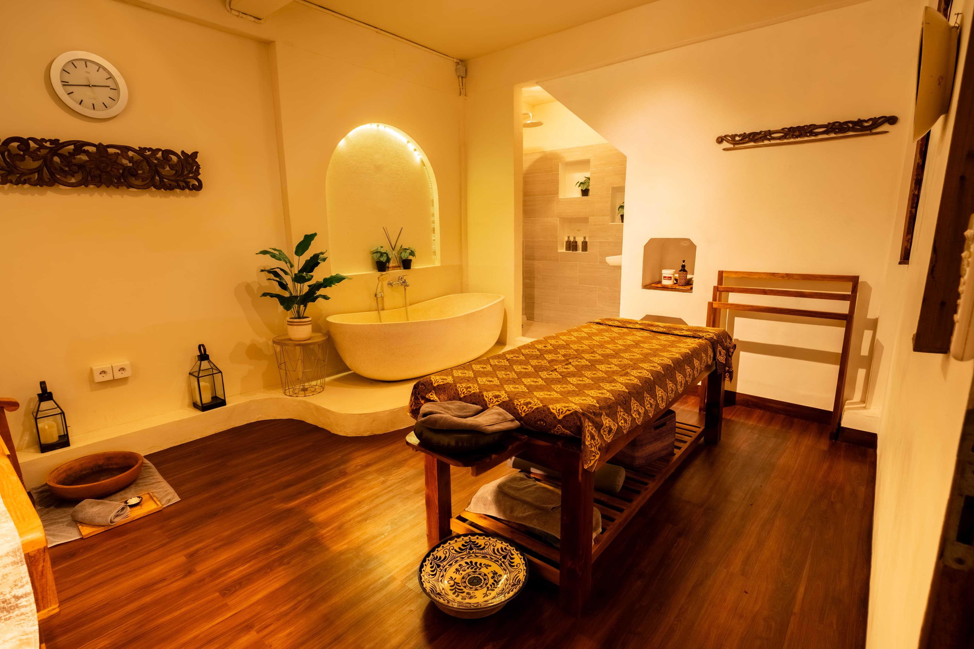 Spacious treatment suite combining a massage bed, soaking tub and en-suite walk-in shower